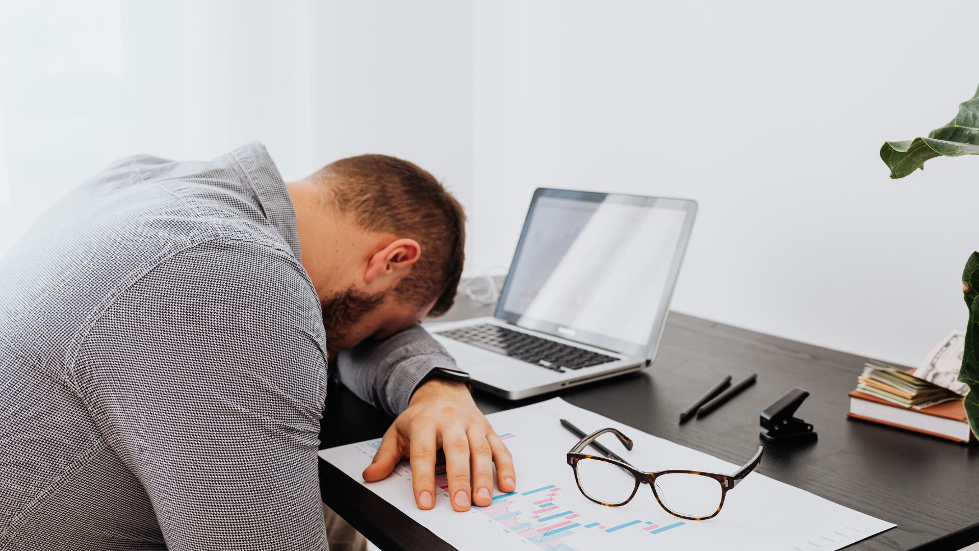 Exhausted person sitting with head in hands, surrounded by dim lighting